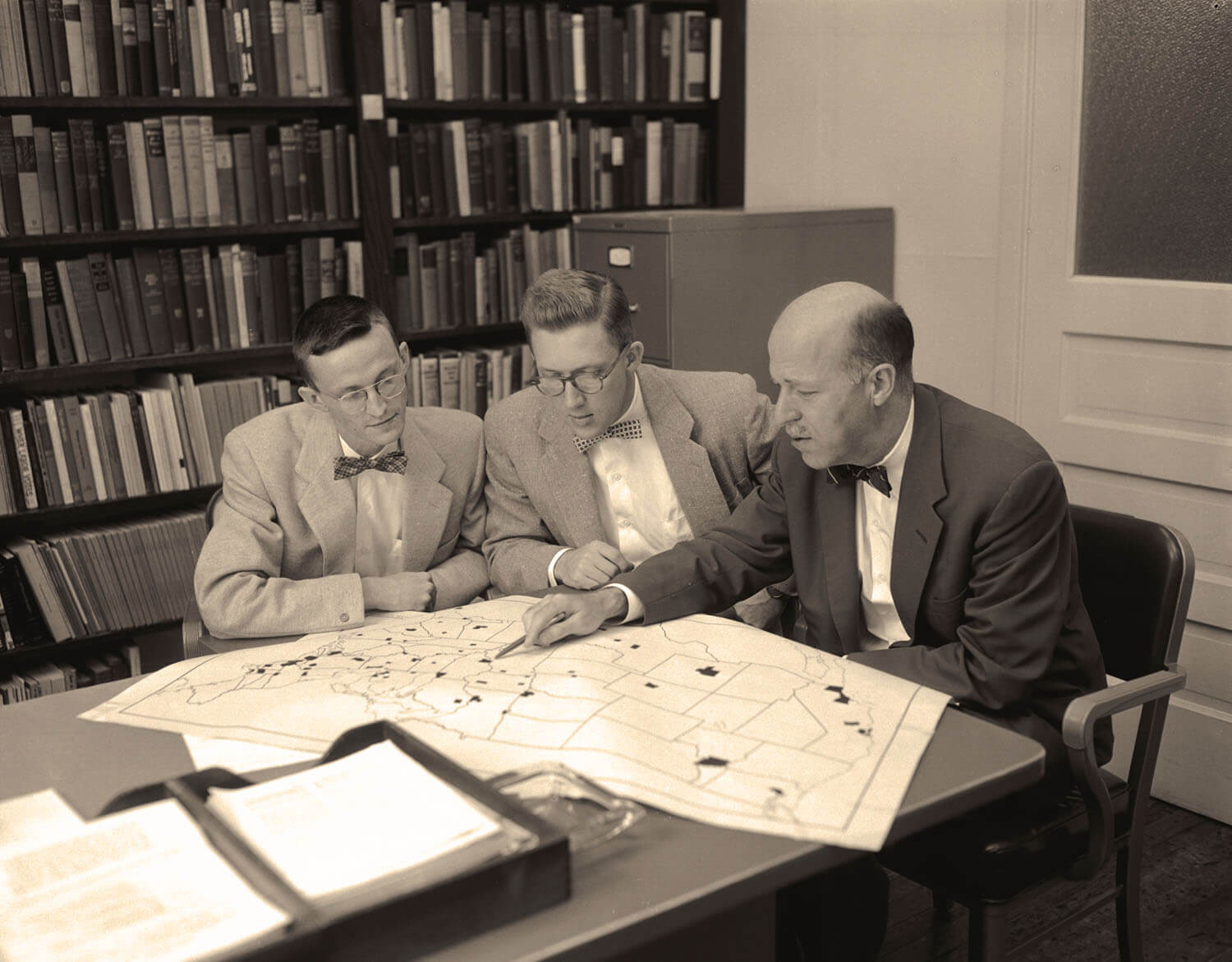 Photo of Converse, Miller and Campbell looking at a map.